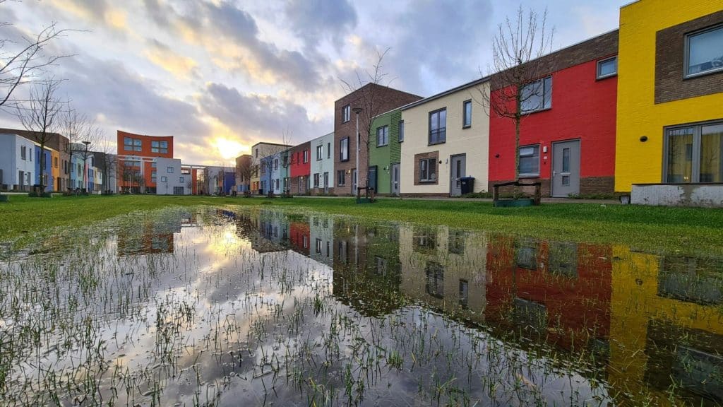 Kleurrijke woningen langs een groene wadi in Woensel-West